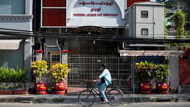 Seorang wanita mengendarai sepedanya di depan markas besar partai Liga Nasional untuk Demokrasi (NLD) di Yangon, Myanmar (1/2). Foto: Stringer/REUTERS