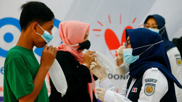 Para penumpang meniup kantong plastik untuk mengambil sampel udara yang akan diuji menggunakan GeNose di sebuah stasiun kereta api di Jakarta, Indonesia, Rabu (3/2). Foto: Ajeng Dinar Ulfiana/REUTERS