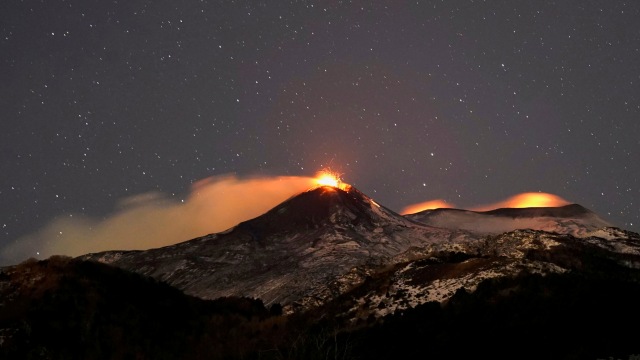 Aliran besar lava panas merah melesat ke langit malam saat Gunung Etna erupsi, terlihat dari desa Catania, Italia, Senin (15/2/2021). Foto: Antonio Parrinello/REUTERS