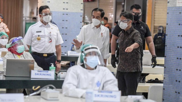Presiden Joko Widodo (tengah) didampingi Menteri Kesehatan Budi Gunadi Sadikin (kanan) dan Gubernur DKI Jakarta Anies Baswedan meninjau vaksinasi COVID-19 massal bagi pedagang di Pasar Tanah Abang Blok A, Jakarta, Rabu (17/2/2021). Foto: Hafidz Mubarak A/ANTARA FOTO