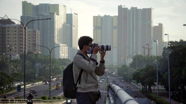 Fotografer mengabadikan area kota dengan kameranya. Foto: Jamal Ramadhan/kumparan