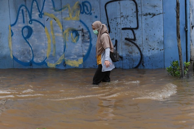 Seorang warga menerobos banjir di Jalan Wolter Monginsidi, Kebayoran, Jakarta, Sabtu (20/2).  Foto: Wahyu Putro A/ANTARA FOTO
