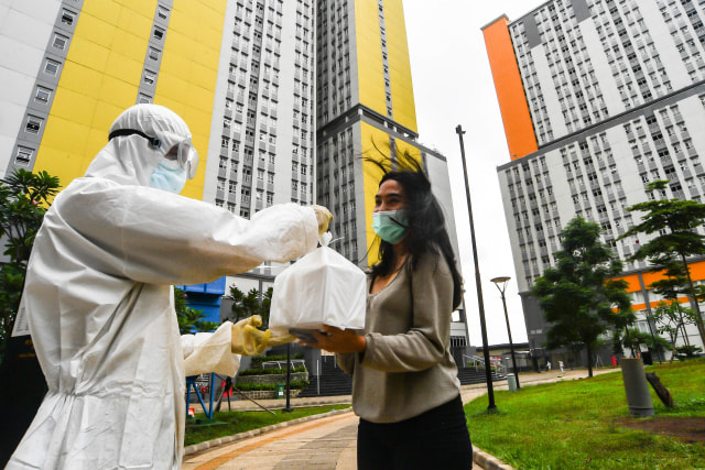 Petugas kesehatan Rumah Sakit COVID-19 Wisma Atlet menyerahkan makanan pesanan pasien di Jakarta, Jumat (26/2/2021). Foto: Muhammad Adimaja/ANTARA FOTO