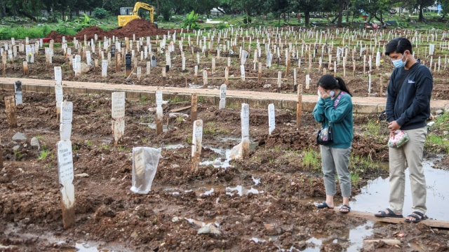 Peziarah berdoa di depan makam keluarganya di areal pemakaman khusus dengan protokol COVID-19 di TPU Bambu Apus, Jakarta Timur, Selasa (2/3/2021). Foto: M Risyal Hidayat/ANTARA FOTO