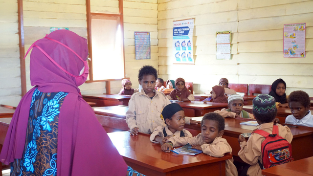 Seorang guru dengan masker di wajahnya mengajar sejumlah murid yang tirai menggunakan masker di SD Al Maarif 1 Kampung Maibo, Kabupaten Sorong, Papua Barat, Sabtu (6/3/2021). Foto: Olha Mulalinda/ANTARA FOTO