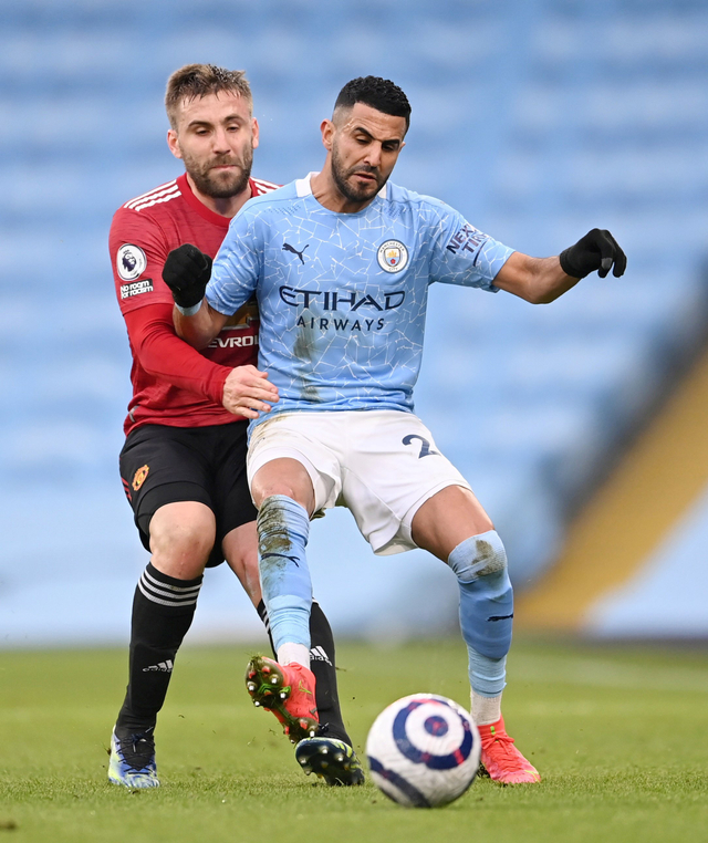 Man City vs MU. Riyad Mahrez berebut bola dengan Luke Shaw pada pertandingan lanjutan Premier League di Etihad Stadium, Manchester, Inggris. Foto: Laurence Griffiths/Pool/REUTERS