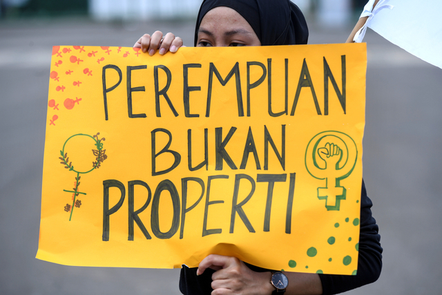 Seorang perempuan membentangkan poster saat melakukan aksi unjuk rasa memperingati Hari Perempuan Internasional di Patung Kuda Arjuna Wiwaha, Jakarta, Senin (8/3/2021). Foto: Hafidz Mubarak A/ANTARA FOTO