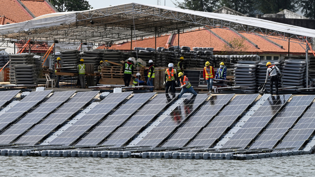 Para pekerja yang merakit panel surya di pantai waduk Tengeh sebagai bagian dari pembangunan pembangkit listrik tenaga surya terapung di Singapura. Foto: ROSLAN RAHMAN/AFP