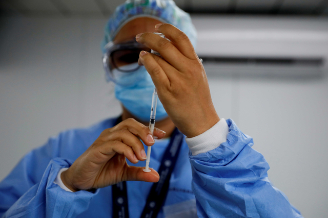 Seorang petugas kesehatan menyiapkan dosis vaksin AstraZeneca (SKBio Corea) di sebuah pusat kesehatan umum. Foto: Jose Cabezas/Reuters