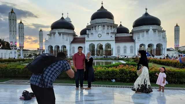 Arul memotret pengunjung Masjid Raya Bairurrahman, Banda Aceh. Foto: Habil Razali/acehkini 
