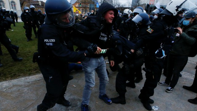 Petugas kepolisian mengeluarkan demonstran dari alun-alun saat berunjuk rasa menentang pembatasan COVID-19 pemerintah di Kassel, Jerman (20/3). Foto: Thilo Schmuelgen/Reuters