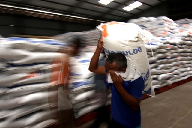 Pekerja mengangkut beras di Gudang Bulog Ketapang II, Banyuwangi, Jawa Timur, Senin (22/3). Foto: Budi Candra Setya/Antara Foto