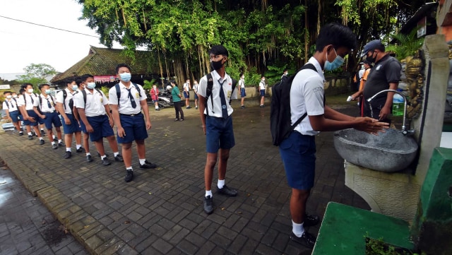 Siswa mencuci tangan saat akan memasuki area sekolah dalam pembelajaran tatap muka (PTM) di SMP Negeri Hindu 2 Sukawati, Gianyar, Bali. Foto: Nyoman Hendra Wibowo/ANTARA FOTO