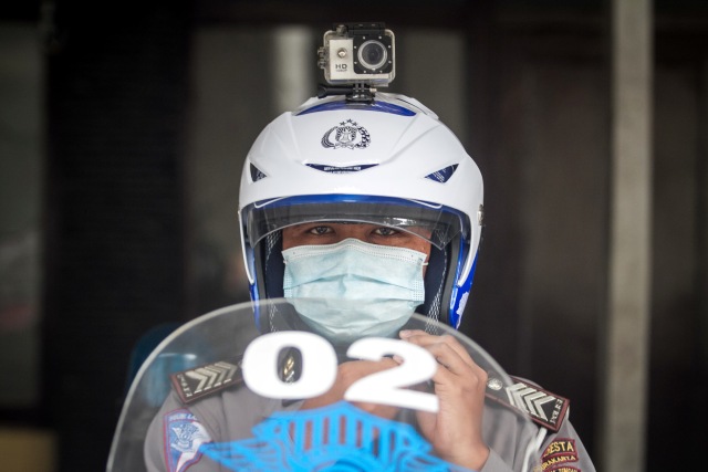 Polisi Lalu Lintas (Polantas) mencoba helm yang dilengkapi kamera portabel pengawas tilang elektronik atau ETLE di TMC Satlantas Polresta, Solo. Foto: Mohammad Ayudha/Antara Foto