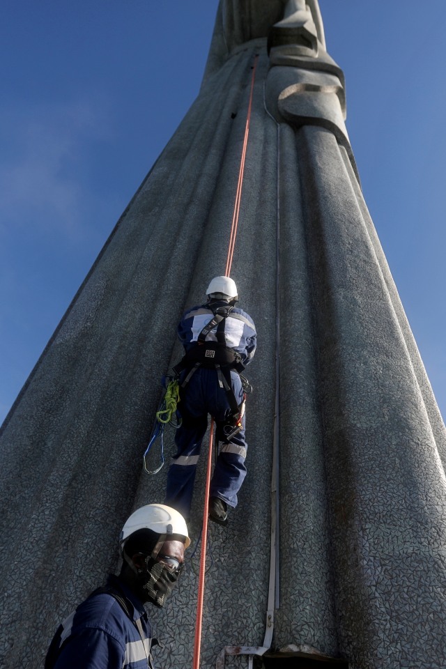Para pekerja memanjat patung Christ the Redeemer untuk melakukan pemugaran, menjelang hari jadinya ke-90, di Rio de Janeiro, Brasil, Rabu (24/3). Foto: Pilar Olivares/REUTERS