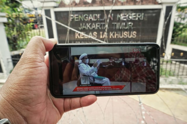Awak media menyiarkan siaran langsung Habib Rizieq di depan PN Jaktim setelah polisi melarang masuk wartawan untuk meliput. Foto: Jamal Ramadhan/kumparan