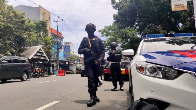 Petugas polisi bersenjata berjaga di lokasi dugaan bom bunuh diri di depan Gereja Katedral Makassar, Sulawesi Selatan, Minggu (28/3). Foto: Stringer/REUTERS