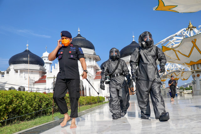 Personel Gegana Polda Aceh saat menyemprotkan disinfektan di Masjid Raya Baiturrahman, Banda Aceh, Jumat (20/3/2020). Foto: Suparta/acehkini
