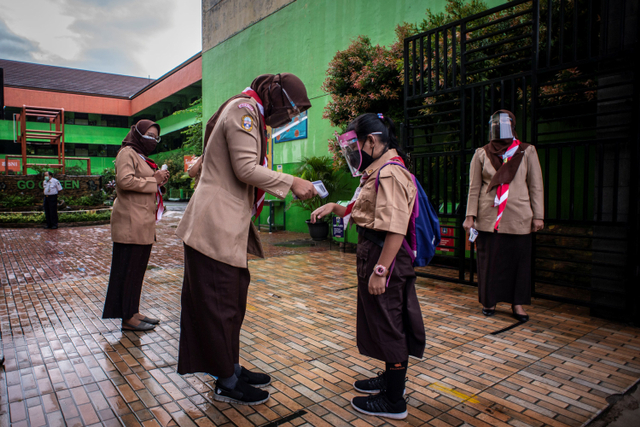 Seorang Guru mengukur suhu tubuh murid pada hari pertama uji coba pembelajaran tatap muka di SD Negeri Kenari 08 Pagi, Jakarta, Rabu (7/4). Foto: Aprillio Akbar/ANTARA FOTO