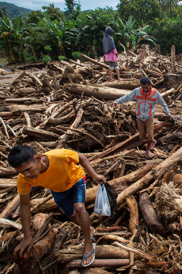Warga melewati tumpukan kayu-kayu yang menyumbat dan merusak salah satu jembatan penghubung antardesa di Adonara Timur, Kabupaten Flores Timur, Nusa Tenggara Timur, Rabu (7/4). Foto: Aditya Pradana Putra/ANTARA FOTO