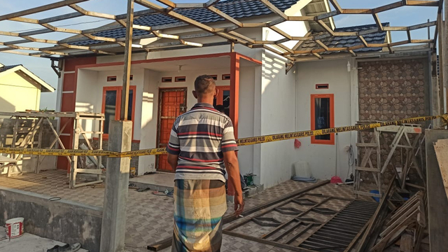 SEORANG warga saat melihat dari luar garis pembatas polisi di Perumahan Berkah Family Village, Jalan Teropong, Siak Hulu, Kampar, Riau, Kamis (8/4/2021). 