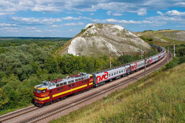 Ilustrasi kereta melintas pada jalur rel yang melewati pegunungan. (Shatrishche Hill and ChS4T locomotive, Voronezh Oblast, Russia. Алексей Задонский. Wikipedia).