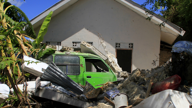 Satu unit kendaraan roda empat tertimpa tembok rumah yang hancur akibat tanah longsor di Kelurahan Oebufu Kota Kupang, NTT, Rabu (14/4). Foto: Kornelis Kaha/ANTARA FOTO