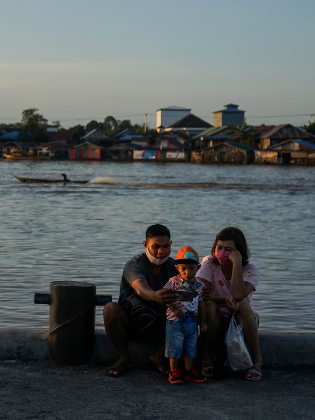 Warga berfoto sambil ngabuburit di Pelabuhan Rambang, Palangkaraya, Kalimantan Tengah, Kamis (15/4). Foto: Makna Zaezar/Antara Foto
