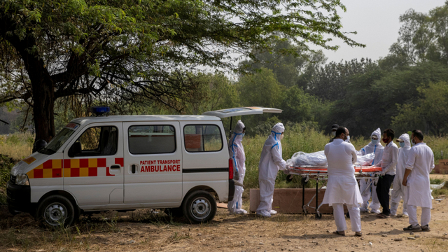 Petugas kesehatan menurunkan jenazah COVID-19 yang akan dikubur di pemakaman di New Delhi, India, Jumat (16/4). Foto: Danish Siddiqui/REUTERS