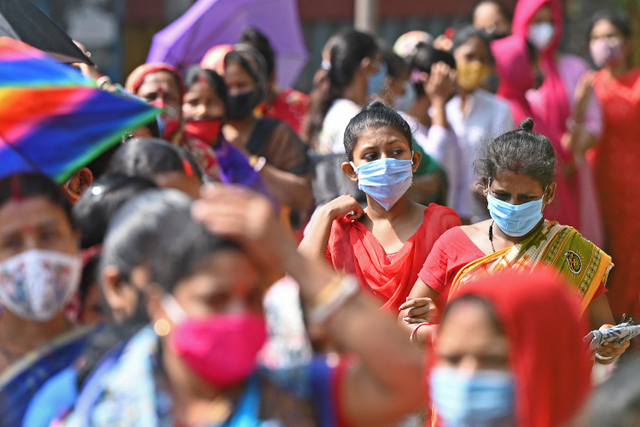 Para pemilih berdiri dalam antrian di tempat pemungutan suara untuk pemilihan majelis legislatif negara bagian Bengal Barat di Kolkata, India, Sabtu (17/4). Foto: Dibyangshu SARKAR / AFP
