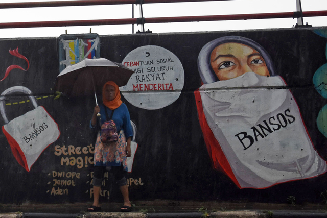 Warga melintas di dekat mural bertema korupsi bansos di Jalan Raya Transyogi, Cileungsi, Kabupaten Bogor, Jawa Barat, Senin (19/4/2021). Foto: Indrianto Eko Suwarso/ANTARA FOTO