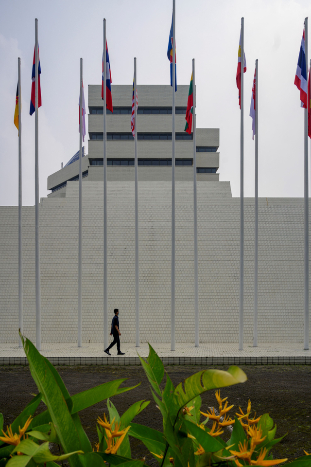 Seorang petugas keamanan berjalan melewati bendera negara-negara ASEAN di gedung sekretariat ASEAN di Jakarta, Selasa (20/4).  Foto: BAY ISMOYO / AFP