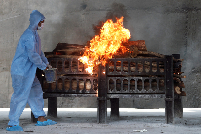 Pekerja mengenakan alat pelindung diri (APD) melihat proses kremasi jenazah yang meninggal karena virus corona di sebuah krematorium, Mumbai, India, Kamis (15/4).  Foto: Francis Mascarenhas REUTERS