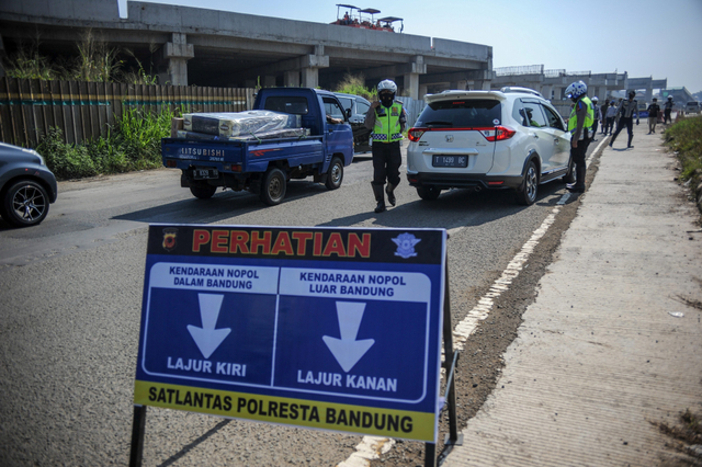 Petugas gabungan memberhentikan kendaraan untuk memeriksa kelengkapan surat dari pengendara dengan kendaraan nomor polisi luar Bandung di gerbang keluar Tol Cileunyi. Foto: Raisan Al Farisi/Antara Foto