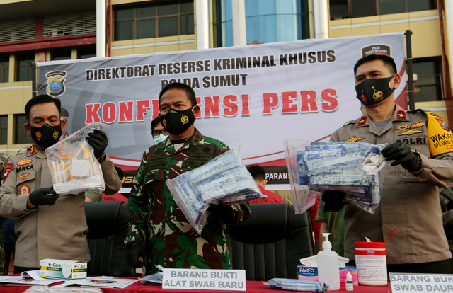 Kapolda Sumatera Utara Irjen Pol Panca Putra Simanjuntak (kiri), Pangdam I/Bukit Barisan Mayjen TNI Hassanudin (tengah) menunjukan barang bukti alat swab tes cepat. Foto: Adiva Niki/Antara Foto