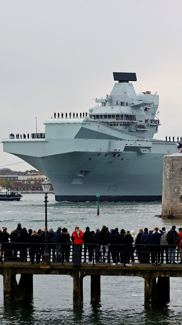 Sejumlah orang menyaksikan kapal induk HMS Queen Elizabeth meninggalkan Pangkalan Angkatan Laut Portsmouth di pantai selatan Inggris, Sabtu (1/5). Foto:  Adrian DENNIS/AFP