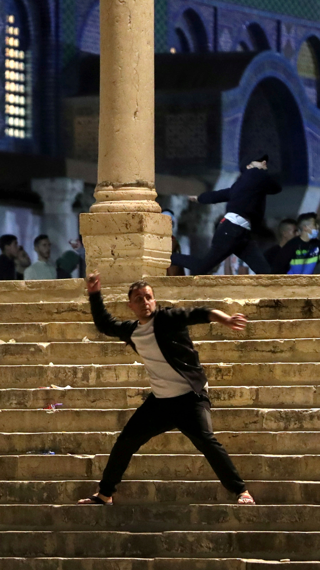 Seorang warga Palestina melemparkan batu ke polisi Israel selama bentrokan di kompleks Masjid Al-Aqsa, di Kota Tua Yerusalem, Jumat (7/5). Foto: Ammar Awad/REUTERS