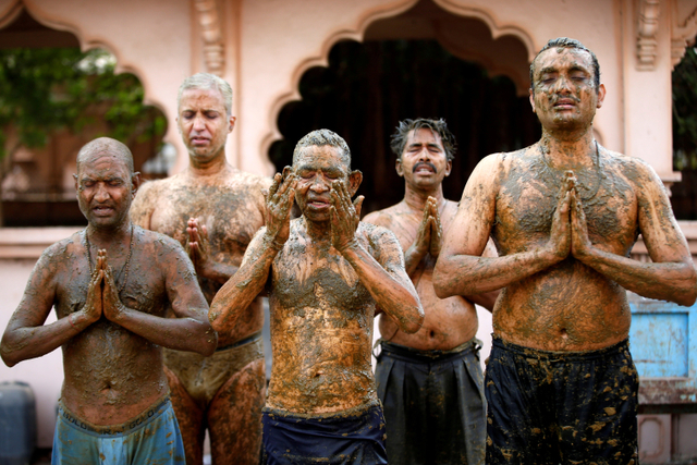 Sejumlah warga berdoa usai mengoleskan kotoran sapi ke tubuhnya selama 'terapi kotoran sapi' untuk meningkatkan kekebalan tubuh melawan virus corona di penampungan sapi Ahmedabad, India.  Foto: Amit Dave/REUTERS