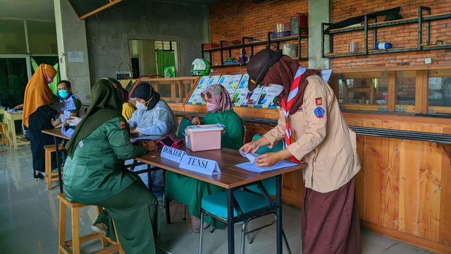 Anggota Pramuka sedang membantu vaksinasi Covid-19. (Kominfo Kwarcab Bogor)