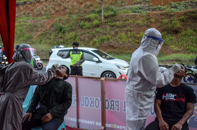 Petugas mengambil sampel lendir hidung kepada pemudik saat pemeriksaan tes cepat (rapid test) Antigen COVID-19 di Jalur Selatan Pos penyekatan leter U Gentong. Foto: Adeng Bustomi/Antara Foto