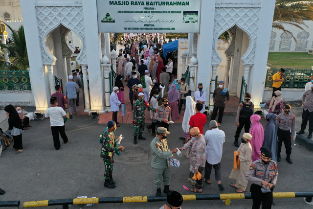 Aparat keamanan membagikan masker kepada jemaah salat Idul Fitri di Masjid Raya Baiturrahman, Banda Aceh, Kamis (13/5/2021). Foto: Abdul Hadi/acehkini 