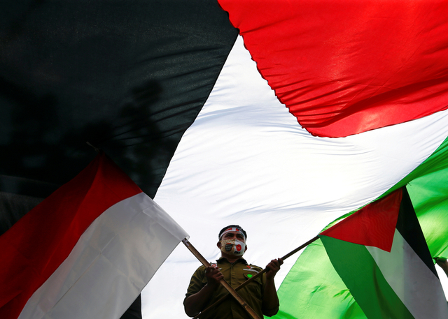 Massa aksi mengibarkan bendera Indonesia dan Palestina saat mengikuti aksi solidaritas di depan Kedubes Amerika Serikat, Jakarta, Kamis (20/5/2021). Foto: Ajeng Dinar Ulfiana/REUTERS