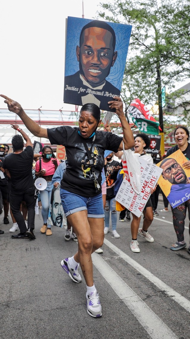 Seorang wanita mengangkat poster saat mengikuti peringatan satu tahun kematian George Floyd, di Minneapolis, Minnesota, AS, Minggu (23/5). Foto: Nicholas Pfosi/REUTERS 
