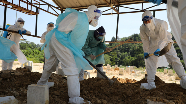 Ulama Muslim Malaysia Rafie Zainal dan anggota timnya membantu anggota keluarga korban COVID-19, saat penguburan di sebuah pemakaman, di Gombak, Malaysia (23/5). Foto: Lim Huey Teng/REUTERS