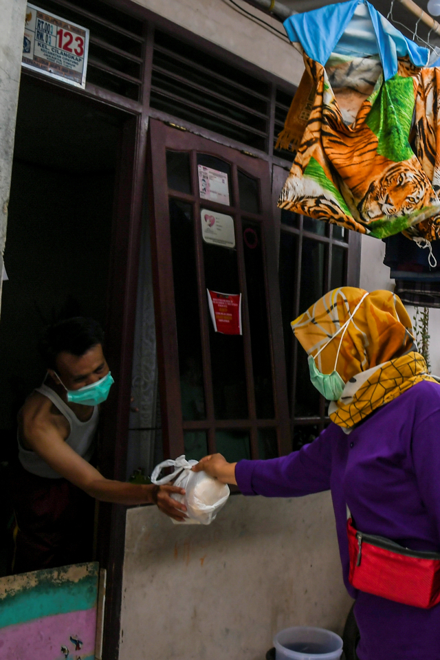 Petugas memberikan paket bahan pangan ke warga yang menjalani isolasi mandiri di Jalan As-Syafiiyah, Cipayung, Jakarta, Jumat (28/5/2021). Foto: Galih Pradipta/ANTARA FOTO