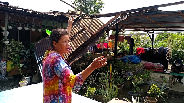 Epi Daulay di depan rumahnya yang rusak akibat angin puting beliung yang terjadi pada Minggu (30/5) sore. (Sumut News)