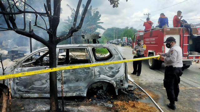 ANGGOTA Polisi memasang garis polisi di lokasi rumah penjual bensin yang terbakar menghanguskan mobil Avanza dan 2 unit sepeda motor, Selasa (1/6/2021). 