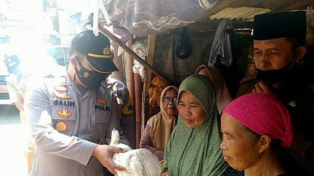 Kapolsek Pacet, Cianjur, Jawa Barat, AKP Galih Apria, saat menyerahkan seekor ayam pada lansia, usai menjalani vaksinasi pertama, Selasa (8/6). Foto: Ahmad FikrI/Antara Foto
