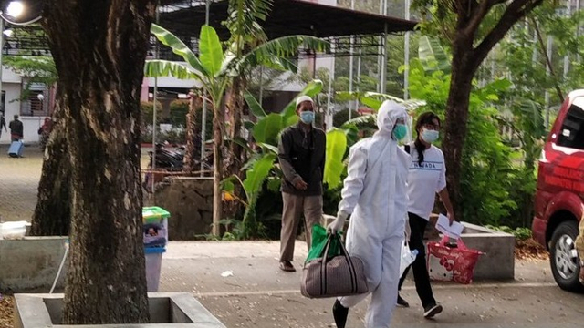 Petugas dengan mengenakan APD mendampingi salah seorang peserta isolasi terpusat yang akan diberangkatkan ke Asrama Haji Donohudan, Kabupaten Boyolali, Jateng. Foto: Akhmad Nazaruddin Lathif/ANTARA