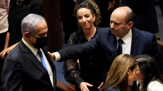 Perdana Menteri Israel yang baru Naftali Bennett (kanan) memberi isyarat kepada Benjamin Netanyahu, di Knesset, parlemen Israel, di Yerusalem, Minggu (13/6). Foto: Ronen Zvulun/REUTERS